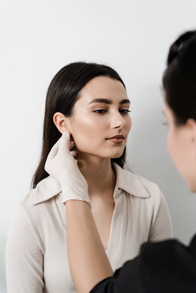 Practitioner examining patient’s earlobe to determine candidacy for earlobe repair treatment